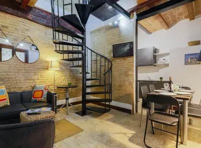 a living room with a spiral staircase in a brick wall at DUPLEX NEAR THE BEACH Barceloneta in Barcelona