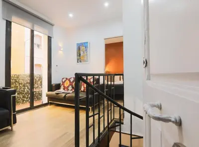 a living room with a couch and a staircase at DUPLEX NEAR THE BEACH Barceloneta in Barcelona