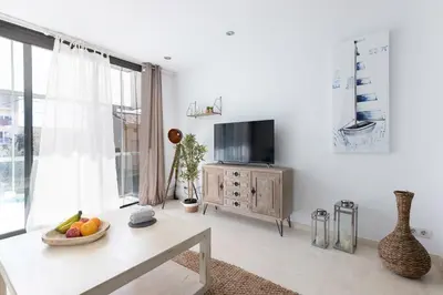 a white living room with a tv and a table at vilasardemarlux3 in Vilassar de Mar