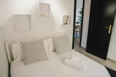 a white bed with two pillows and a mirror at BBarcelona Central Boutique Apartments in Barcelona
