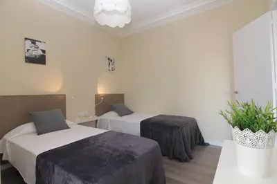 a hotel room with two beds and a potted plant at FELIP - Spacious and quiet apartments & one with Terrace in Barcelona