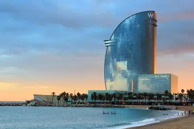 a building on the beach with people in the water at GIRONA - Modernist apartments next to Paseo de Gracia in Barcelona