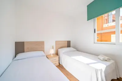 two beds in a small bedroom with a window at HomeHolidaysRentals Moana in Calella