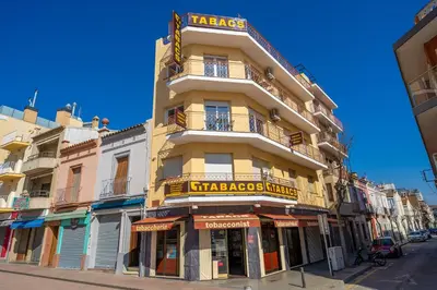 a tall yellow building with a sign on it at HomeHolidaysRentals Moana in Calella