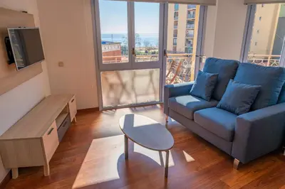 a living room with a blue couch and a table at HomeHolidaysRentals Elodie in Calella