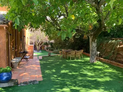a garden with a table and chairs under a tree at Cal Secretari in Rellinars
