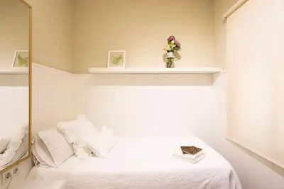 a bedroom with a white bed and a mirror at Chic Gran Via Apartment in Barcelona