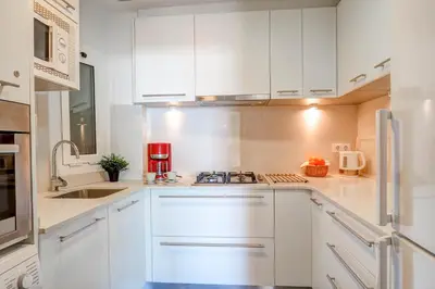 a white kitchen with white cabinets and a sink at La Gioia 1 by Hello Homes Sitges in Sitges