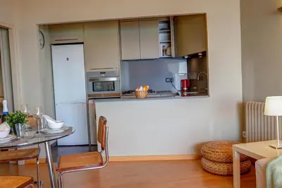 a kitchen with a refrigerator and a table with chairs at La Gioia 3 by Hello Homes Sitges in Sitges
