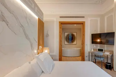 a bedroom with a bed and a tub and a desk at Hotel Boutique Mirlo Barcelona in Barcelona
