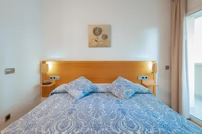 a bed with a blue comforter and two pillows at InSitges Sant Sebastia's Beach in Sitges