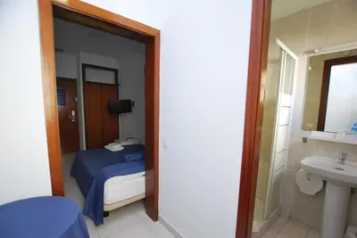 a bedroom with a bed and a bathroom with a sink at Hotel Tres Leones in Vilassar de Mar