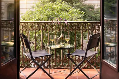 two chairs and a table with wine glasses on a balcony at Amra Barcelona Caspe in Barcelona