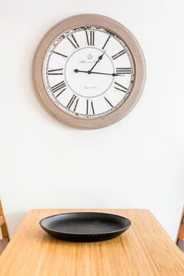 a clock sitting on top of a wooden table at Charming Apartment With Vibrant Accents in Hospitalet de Llobregat