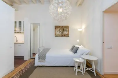 a white bedroom with a bed and a chandelier at Historical Apartment With Awesome Rooftop in Barcelona