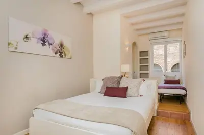a white bedroom with a white bed and a window at Historical Apartment With Awesome Rooftop in Barcelona