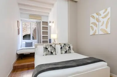 a white bedroom with a bed and a window at Historical Apartment With Awesome Rooftop in Barcelona