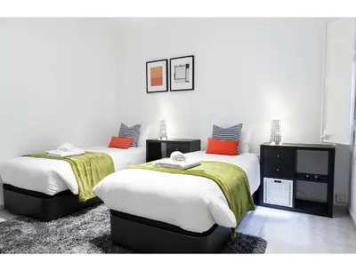 two beds in a room with white walls and orange pillows at CENTRAL STYLISH EIXAMPLE - Casa Antonio By MyRentalHost in Barcelona