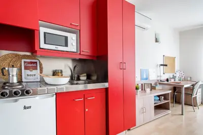 a red kitchen with a sink and a microwave at Alojamientos Universitarios Resa Hipatia in Terrassa