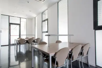 a group of tables and chairs in a room with windows at Alojamientos Universitarios Resa Hipatia in Terrassa