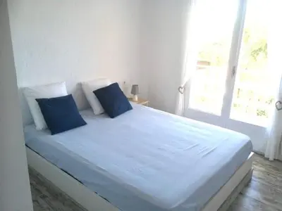 a white bed with blue pillows in a bedroom at CASA DEL BOSQUE CON PISCINA EN SITGES in Sant Pere de Ribes