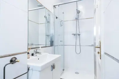 a white bathroom with a sink and a shower at Modernist apartment in the best location, Eixample in Barcelona