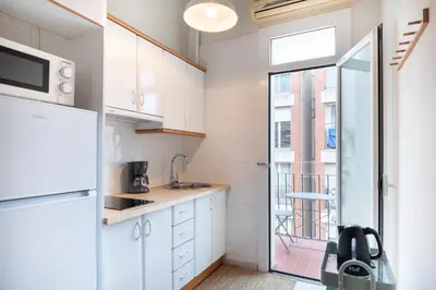 a small kitchen with white cabinets and a window at Cozy Apartment in the Heart of Gracia, Barcelona in Barcelona