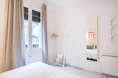 a white bedroom with a bed and a window at Cozy Apartment in the Heart of Gracia, Barcelona in Barcelona
