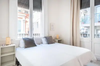 a white bedroom with a large white bed and windows at Cozy Apartment with Terrace in Gracia, Barcelona Local Life in Barcelona