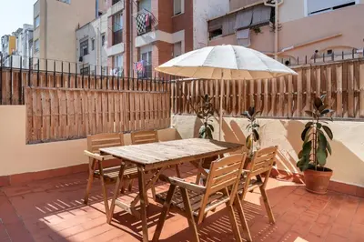 a wooden table with chairs and an umbrella on a patio at Cozy Apartment with Terrace in Gracia, Barcelona Local Life in Barcelona