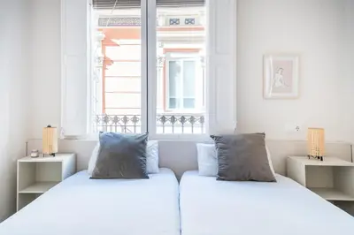 two beds in a white room with a window at Cozy Apartment with Terrace in Gracia, Barcelona Local Life in Barcelona