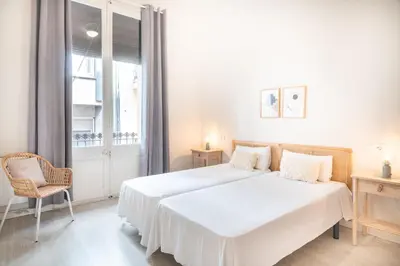 a white bedroom with a large bed and a window at Sunny Terrace Apartment in Gracia, Barcelona - Local Lifestyle in Barcelona