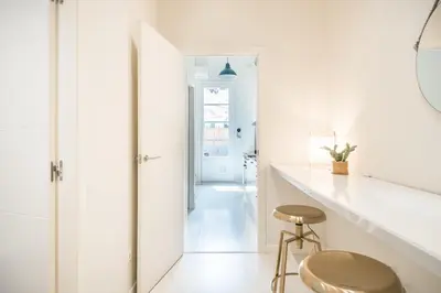 a white hallway with a stool and a mirror at Sunny Apartment with Private Terrace in Gracia, Barcelona in Barcelona