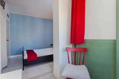 a small bedroom with a red curtain and a red chair at Charming 3 Bdr-2 Bthr In Gracia in Barcelona