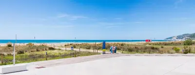 a person walking down a boardwalk near the beach at Maka beach apartment v in Castelldefels