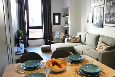 a living room with a couch and a table with a bowl of fruit at Piso nuevo al lado de la Sagrada Familia. in Barcelona