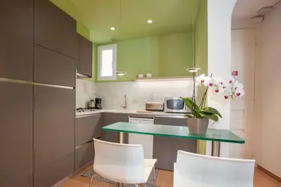 a kitchen with green walls and a table with white chairs at BCNGOTIC 41 in Barcelona