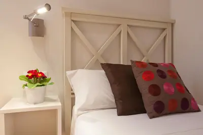 a bed with two pillows and a vase with red flowers at BCNGOTIC 33 in Barcelona