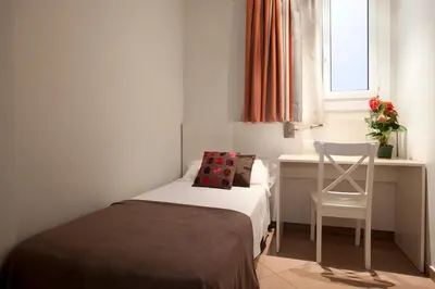 a small bedroom with a bed and a chair at BCNGOTIC 33 in Barcelona