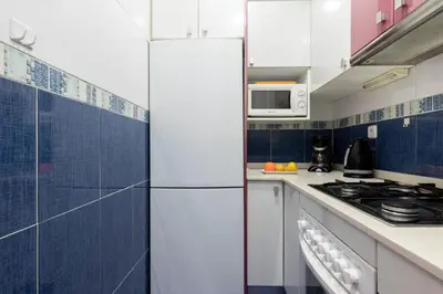 a white refrigerator in a kitchen with blue tiles at AB Rossello Center Terrace in Barcelona