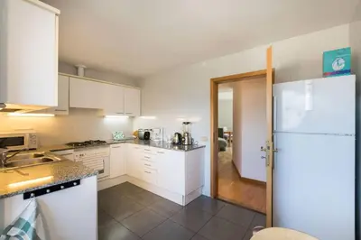 a kitchen with white cabinets and a white refrigerator at Sea views & city skyline in Barcelona