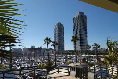 a view of a marina with palm trees and buildings at Sea views & city skyline in Barcelona