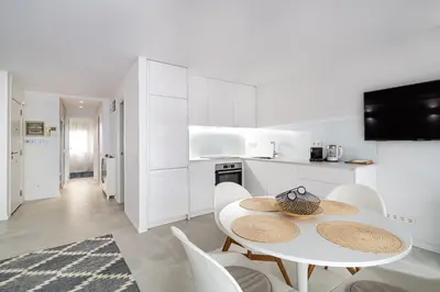 a white kitchen with a white table and chairs at Comtal homey apartments in Barcelona