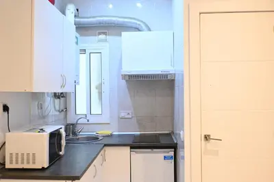 a white kitchen with a microwave and a sink at Homenfun Barcelona Les Corts in Barcelona