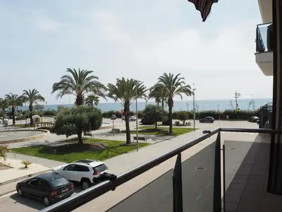 a balcony with cars parked on a street with palm trees at NINFA Apartamento con balcón ideal familias con vistas al mar in Pineda de Mar