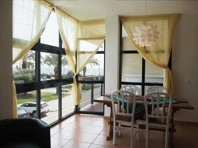 a dining room with a table and chairs and windows at NINFA Apartamento con balcón ideal familias con vistas al mar in Pineda de Mar