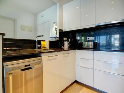 a kitchen with white cabinets and stainless steel appliances at Mediterraneo Seaview Apartment by Hello Homes Sitges in Sitges