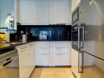 a kitchen with white cabinets and a stainless steel refrigerator at Mediterraneo Seaview Apartment by Hello Homes Sitges in Sitges