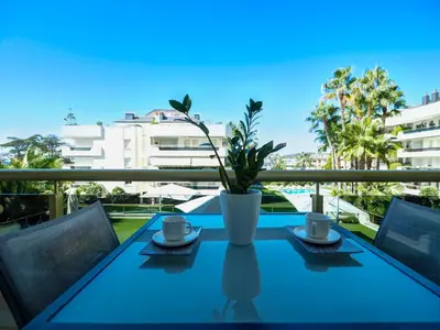 a table with two cups and a potted plant on a balcony at Mediterraneo Seaview Apartment by Hello Homes Sitges in Sitges