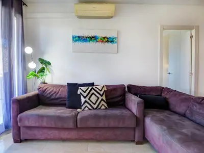 a living room with a purple couch and a painting at Mediterraneo Seaview Apartment by Hello Homes Sitges in Sitges